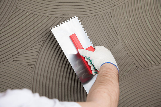 the worker applies glue for a tile on a wall