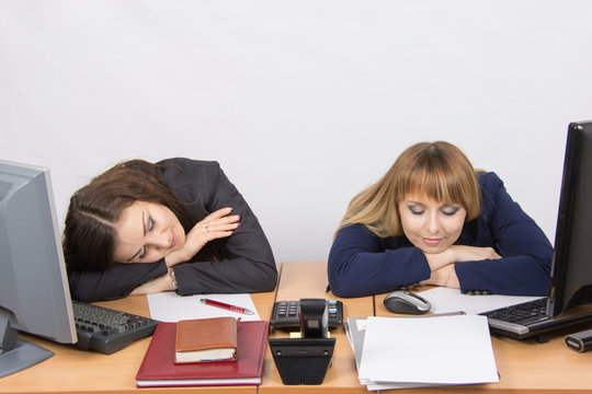 Two young office worker sleeping on desk for computers