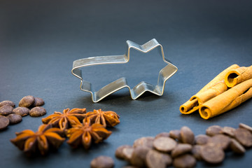 Christmas star cookie cutter, anise stars, cinnamon sticks and chocolate on the black background
