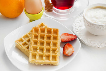Breakfast meal with waffles and strawberries, fresh fruits , tea