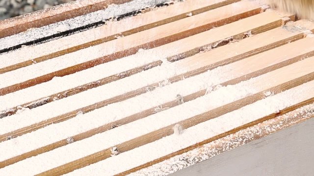 Brushing powdered sugar varroa treatment into bee spaces 