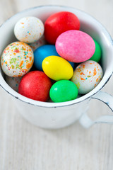 Fototapeta na wymiar Easter candy eggs in miniature cup on wooden surface