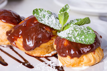 Profiteroles with chocolate sauce and mint leaf