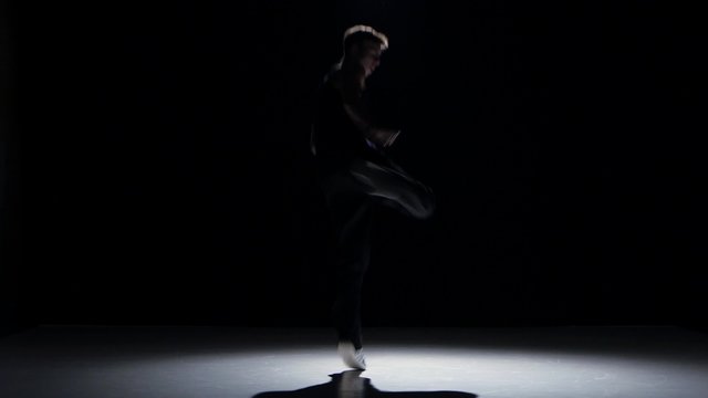 Boy dancing breakdance, on black, shadow
