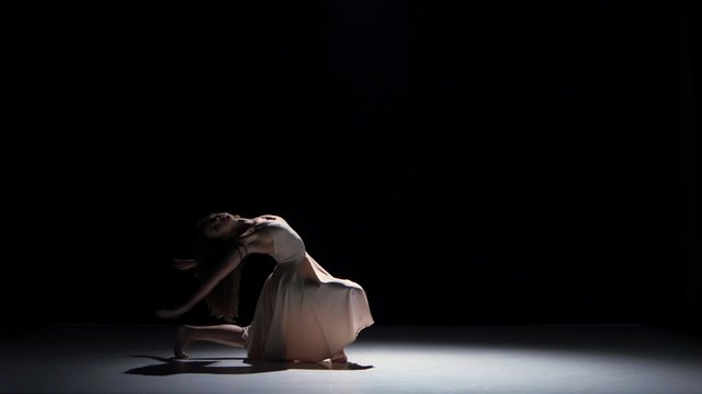 Young woman dancer dancing contemporary dance moves, on black, shadow