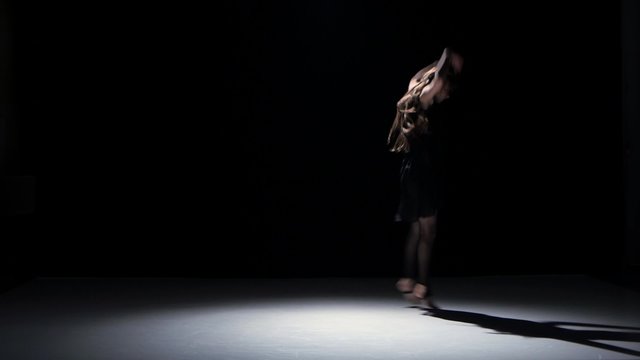 Sensual contemporary dance performance of long-haired dancer on black, shadow