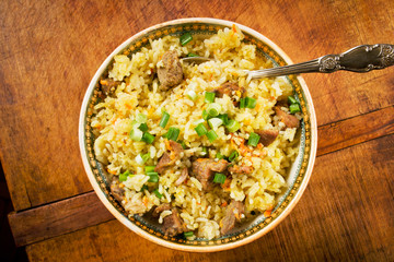 Traditional Asian pilaf in vintage bowl on wooden table