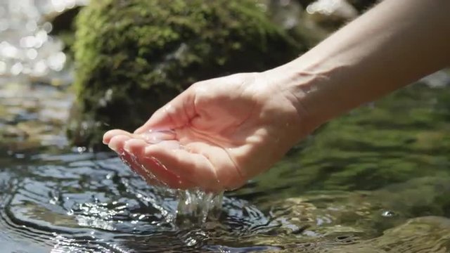 SLOW MOTION: Female holding a crystal clear mountain water