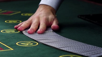Croupier shuffling poker playing cards on green table, slow motion - Powered by Adobe
