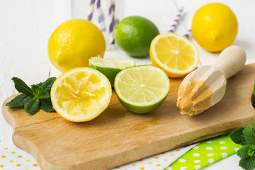 Lemons, limes, mint cocktail preparation on a wooden background