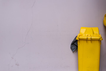 A yellow trash bin with a background of pink crack cement wall