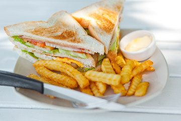 Club sandwich with french fries on a white table