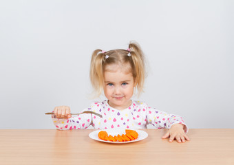 little girl eats carrot with fork.