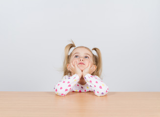 Little girl in casual clothes looking up and thinking