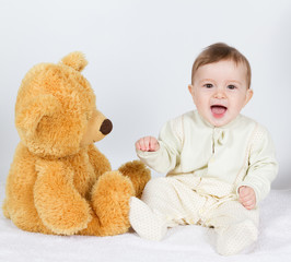 Little boy baby sitting next to a teddy bear