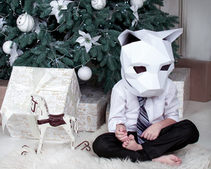 Sad boy in cat mask near christmas teree
