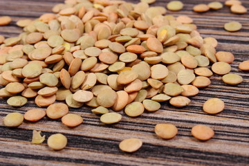 Heap of green lentil on wooden background