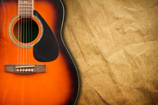 Acoustic guitar resting against a blank grunge background with c