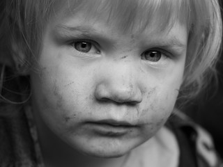 Portrait of a dirty child. The child in the mud smeared face. Black and white