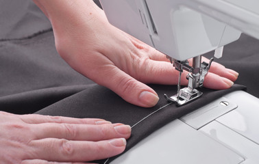 Woman's hands with cloth at sewing machine