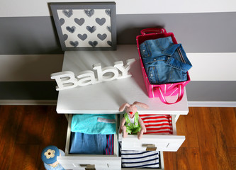 Child clothes in wooden chest of drawer, close up