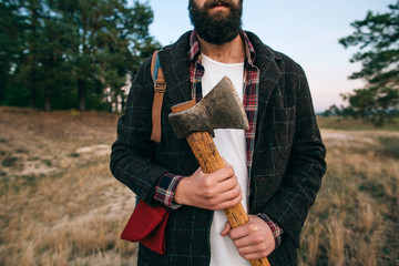 Hipster  portrait brutal bearded and moustached woodcutter Gypsy man in the forest with ax. Travel style