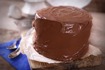 Chocolate cake with two spoons and blue tablecloth on a wooden boards background