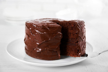 Chocolate cake on plate with a cut piece on unfocused background, closeup