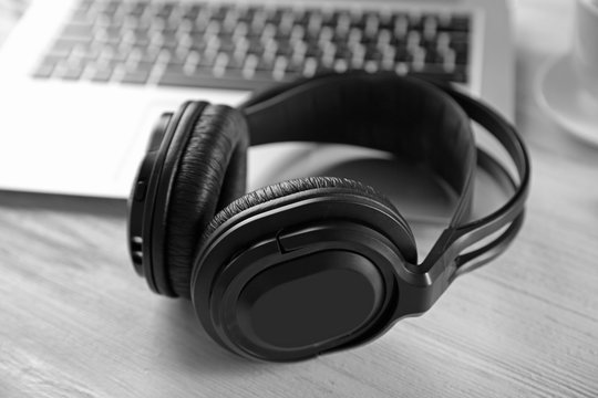 Headphones and laptop on wooden table closeup