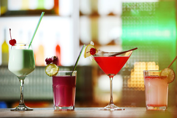 Glasses of cocktails on bar background