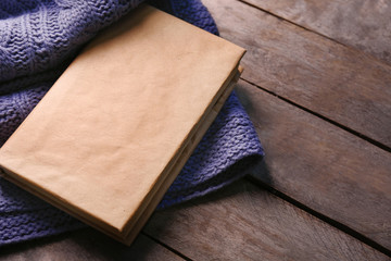 A book and a woolen blanket on wooden background
