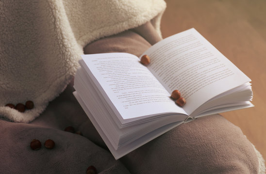 An open book and hazelnuts on soft blanket. Peace and comfort concept