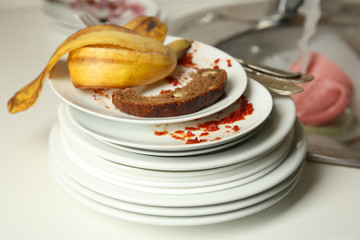 Stack of dirty plates near kitchen sink closeup
