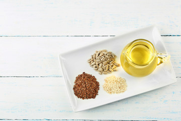 Different kinds of seeds and oil on wooden table