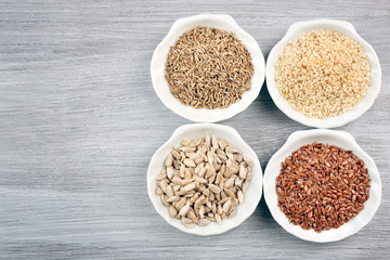 Different kinds of seeds in bowl on wooden table