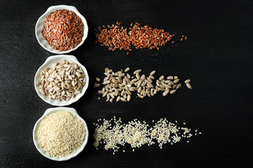Flax, sesame and sunflower seeds on wooden table
