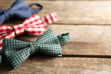 Different bow ties on wooden background