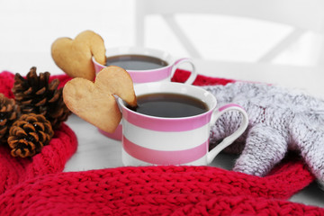 Heart shape cookie on cup of coffee with red knitted scarf closeup