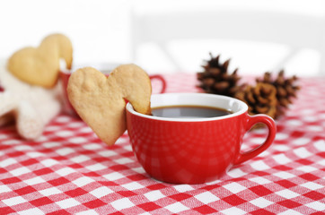 Heart shape cookie on cup of coffee on checkered napkin closeup