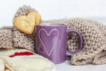 Heart shape cookie on cup of coffee with knitted cloth closeup