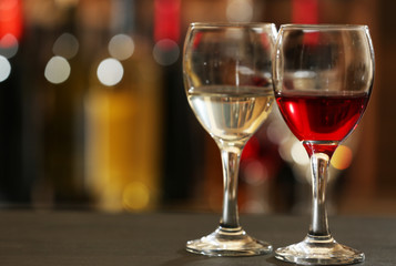 Glasses of red and white wine against blurred background