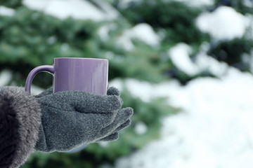 Obraz na płótnie Canvas Female hands holding cup of hot drink at the winter park