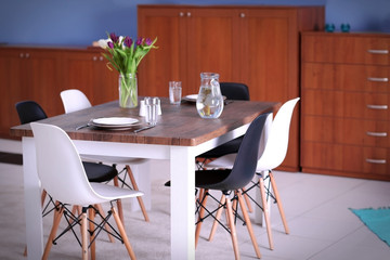 Modern living room. Furniture set with table and chairs. Bouquet of beautiful white and purple tulips on the table