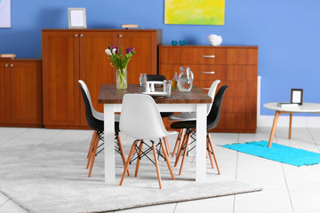 Modern living room. Furniture set with table and chairs. Bouquet of beautiful white and purple tulips on the table