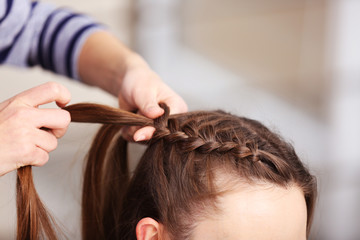 Naklejka premium Professional hairdresser braiding clients hair