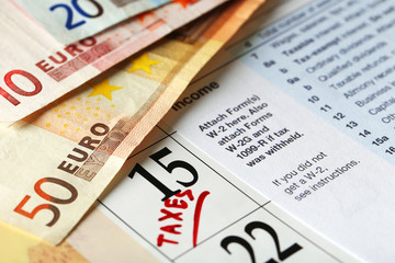 Taxes mark in the calendar with euro bills, close up