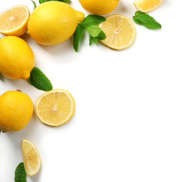 Colorful yellow lemons sliced and halved with mint sprigs isolated on a white background, top view
