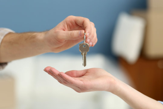 Male hand giving keys from new apartment to female hand on blurred background