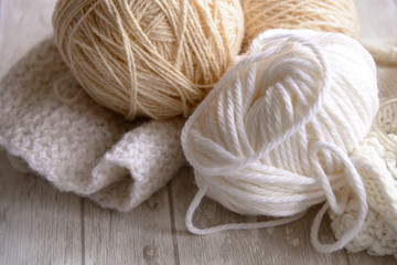 white and beige balls of yarn and knitting needles
