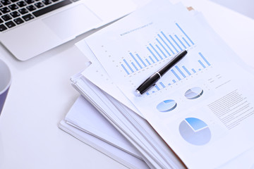 .Office workplace with a laptop and financial documents on the light reflecting table